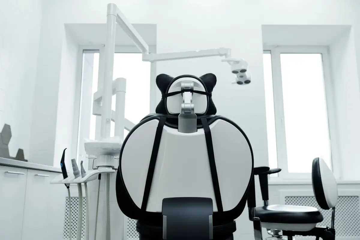 The back of a dental chair in a well-lit treatment room with large windows