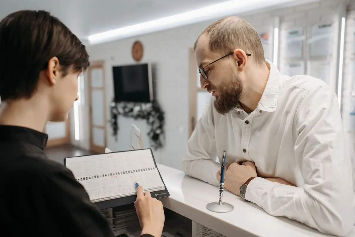A dental front desk where a receptionist and a patient look at the appointment book together